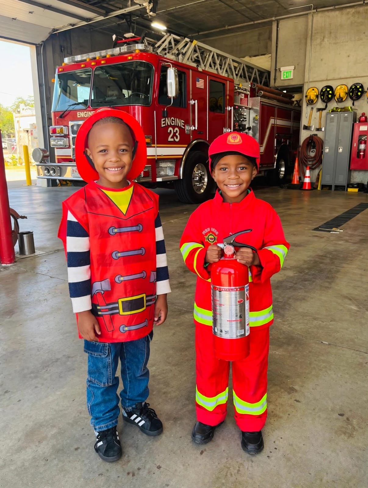 Children dressed as firefighters in front of a fire engine